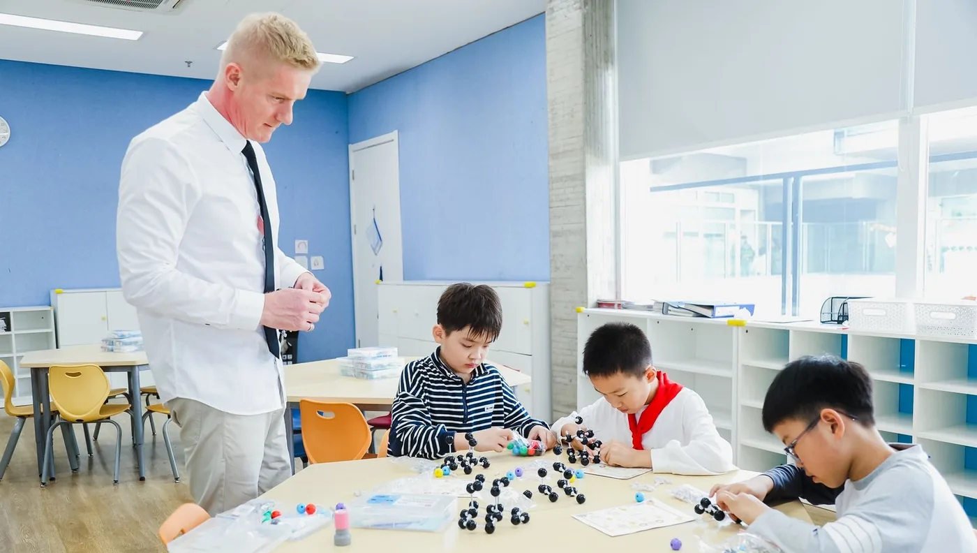 A classroom of learners building models while Werner Guderian looks on